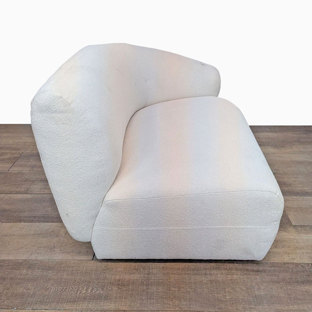 Side view of a cream sofa showing curved silhouette. Made with boucle performance fabric.
