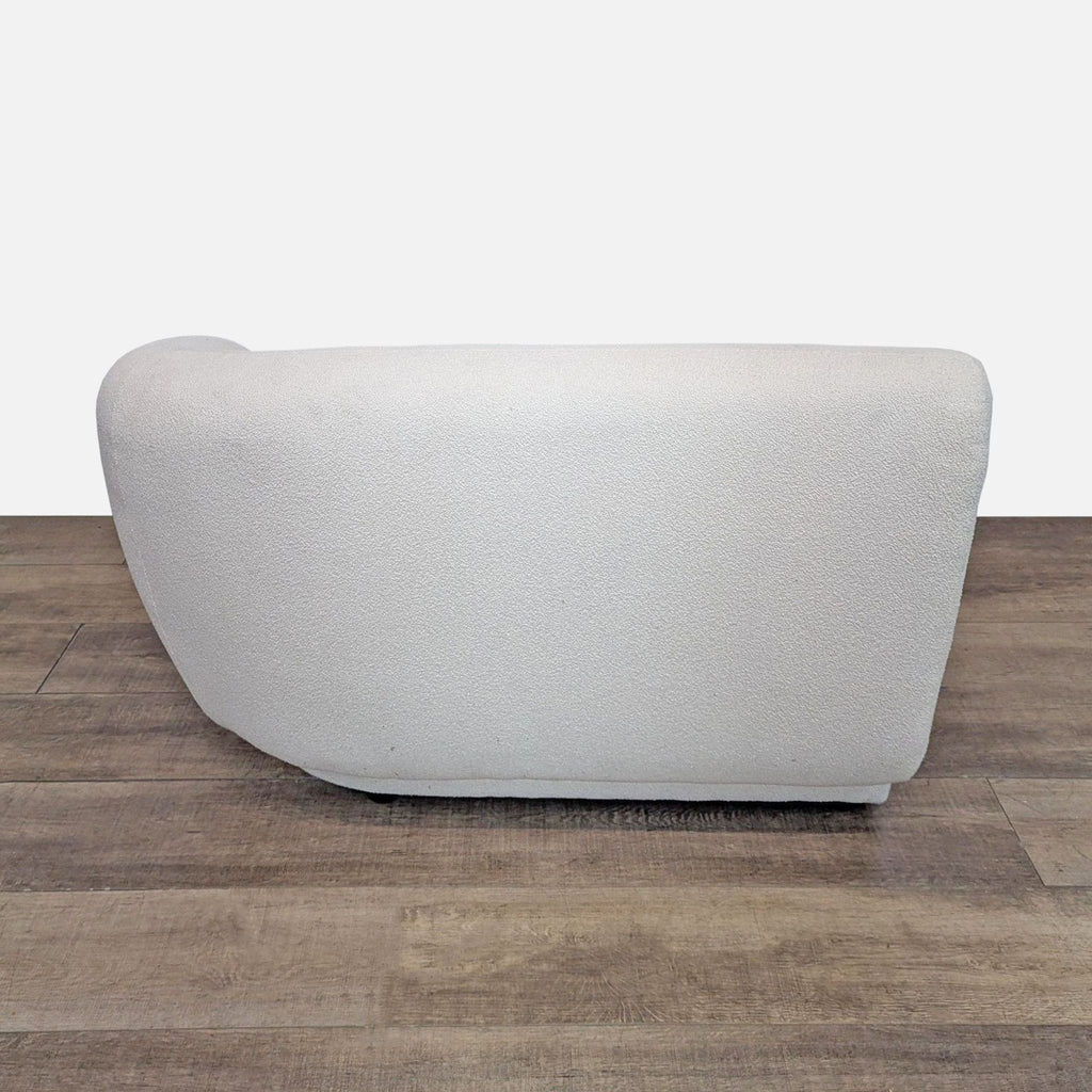 Back view of a cream sofa with a smooth, arched design. Upholstered in boucle fabric.