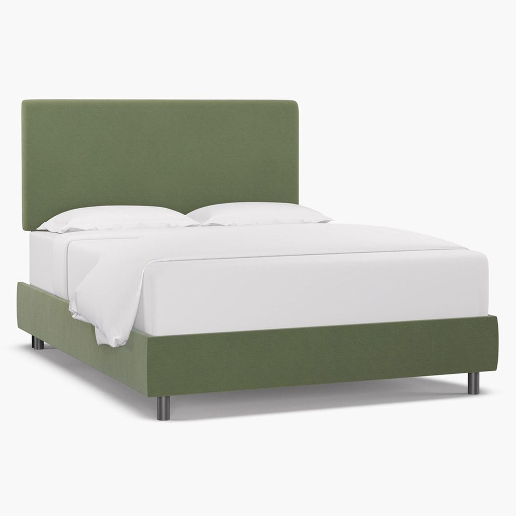 Side view of green velvet upholstered bed frame, no mattress.