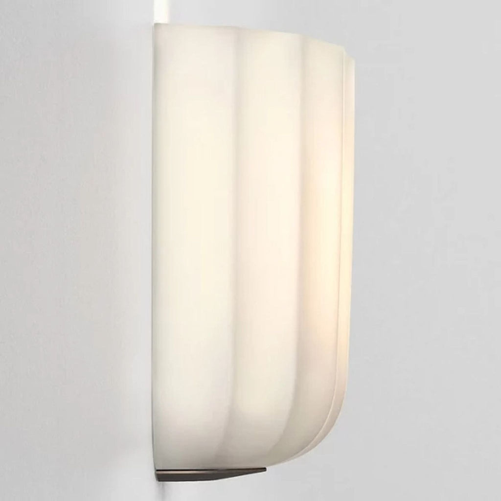 Side view of fluted opal-glass light projecting soft glow, mounted on wall.
