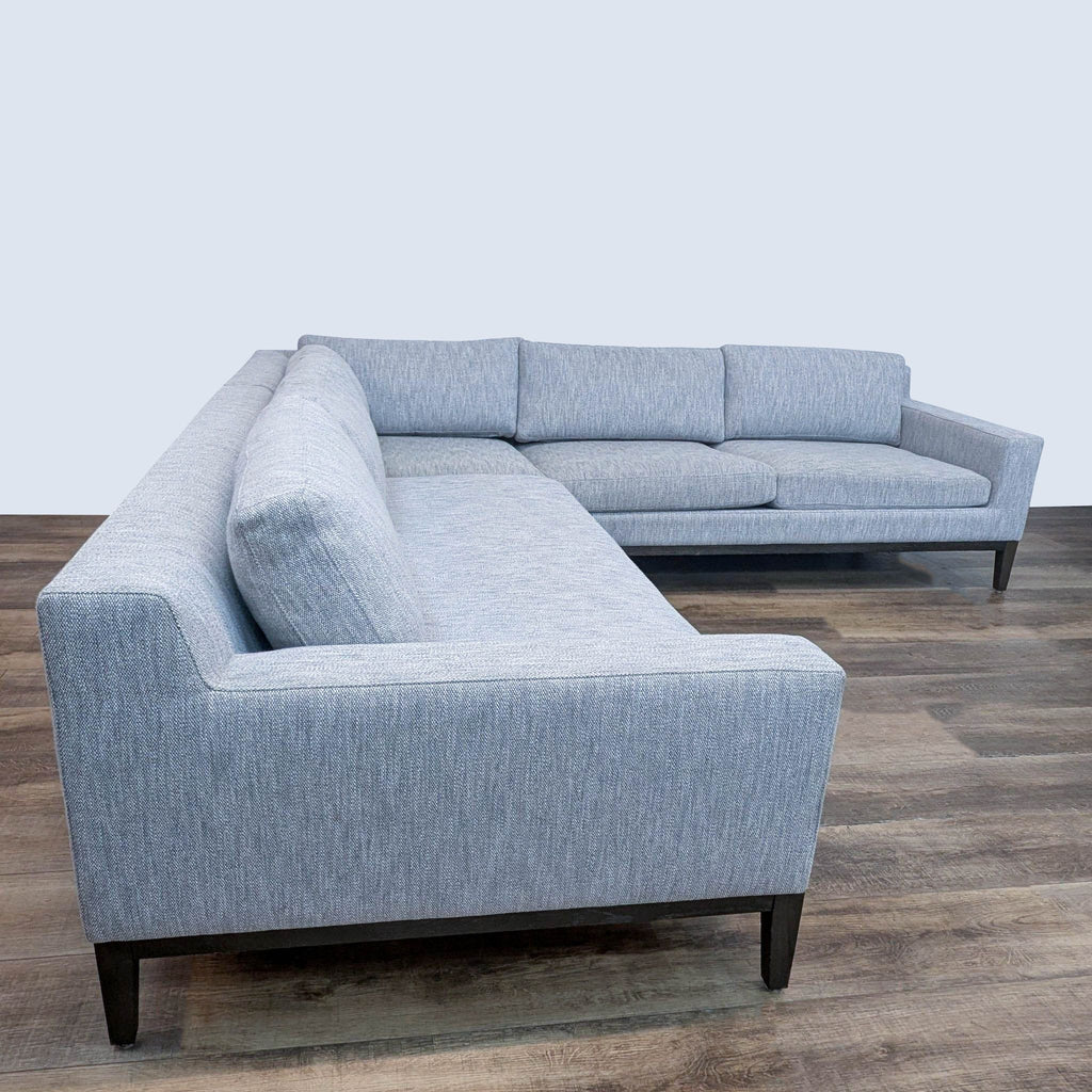 Contemporary sectional sofa featuring sleek design and textured upholstery on wooden legs.  