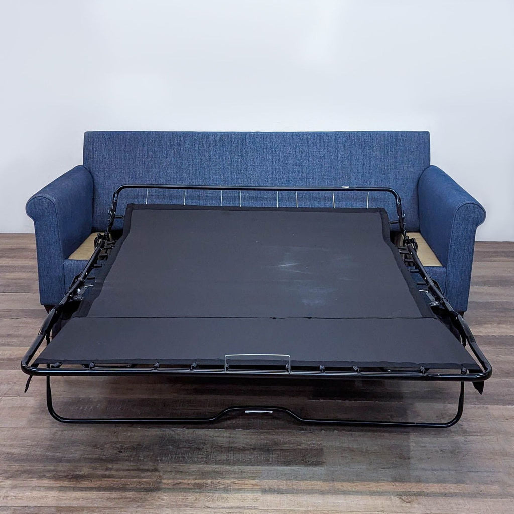 Sofa with queen sleeper pulled out, blue fabric, and rolled arms in a spacious room.