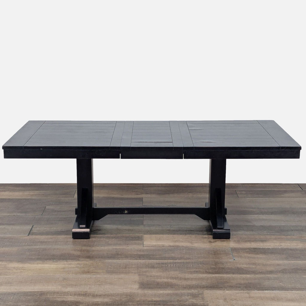 Extendable trestle-style dining table by Cost Plus, shown fully extended on wood floor.
