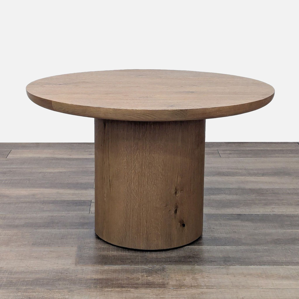 Round dining table with a pedestal base, crafted from American white oak.