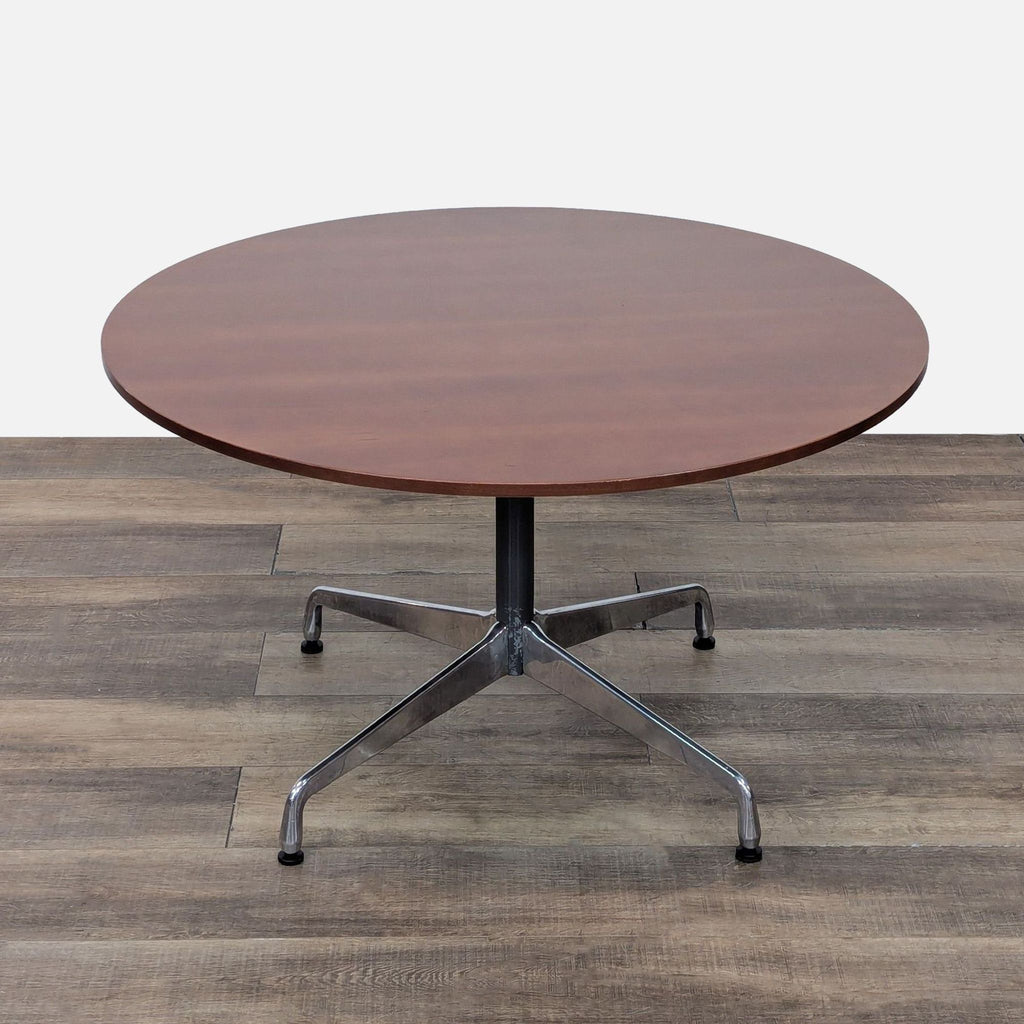 Round Eames Dining Table featuring a sleek base and veneered walnut top on a wood floor.