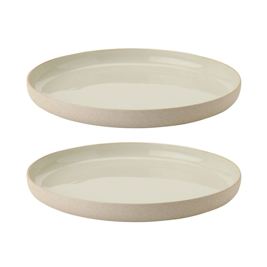 Two beige stoneware plates with a glazed top and raw, unfinished edges, designed by HolmbäckNordentoft.