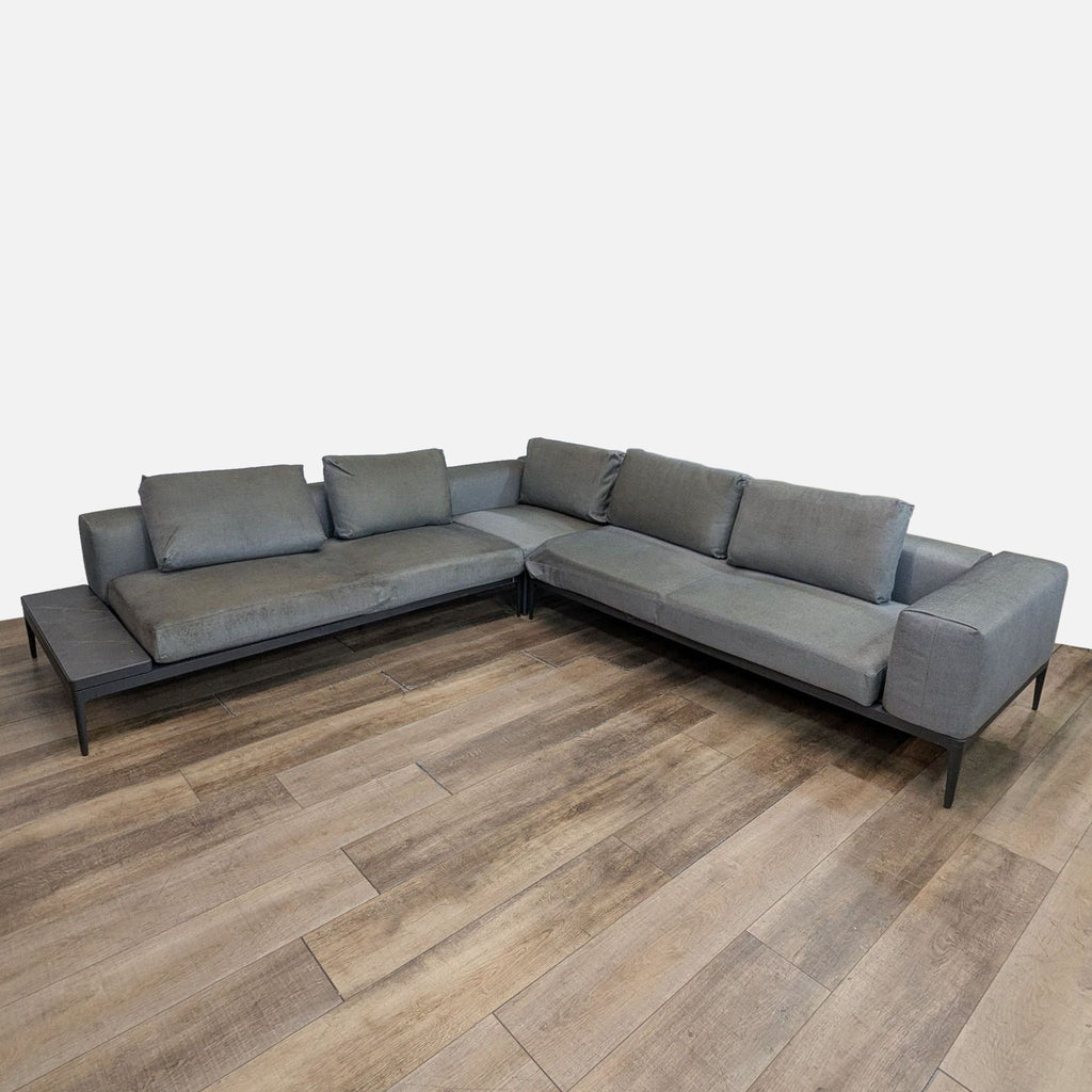 Outdoor patio sofa with gray cushions and ceramic side table.