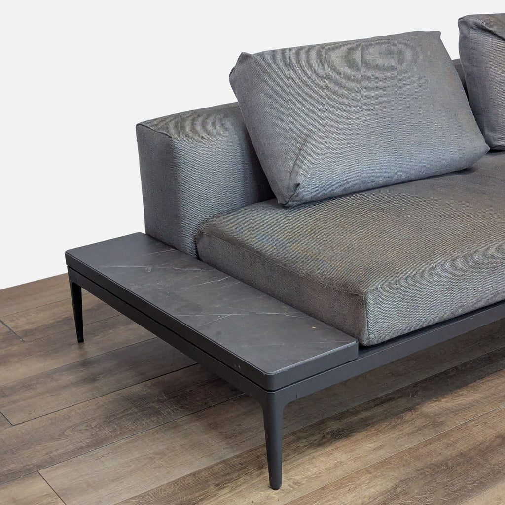 Close-up of gray patio sofa with ceramic side table.