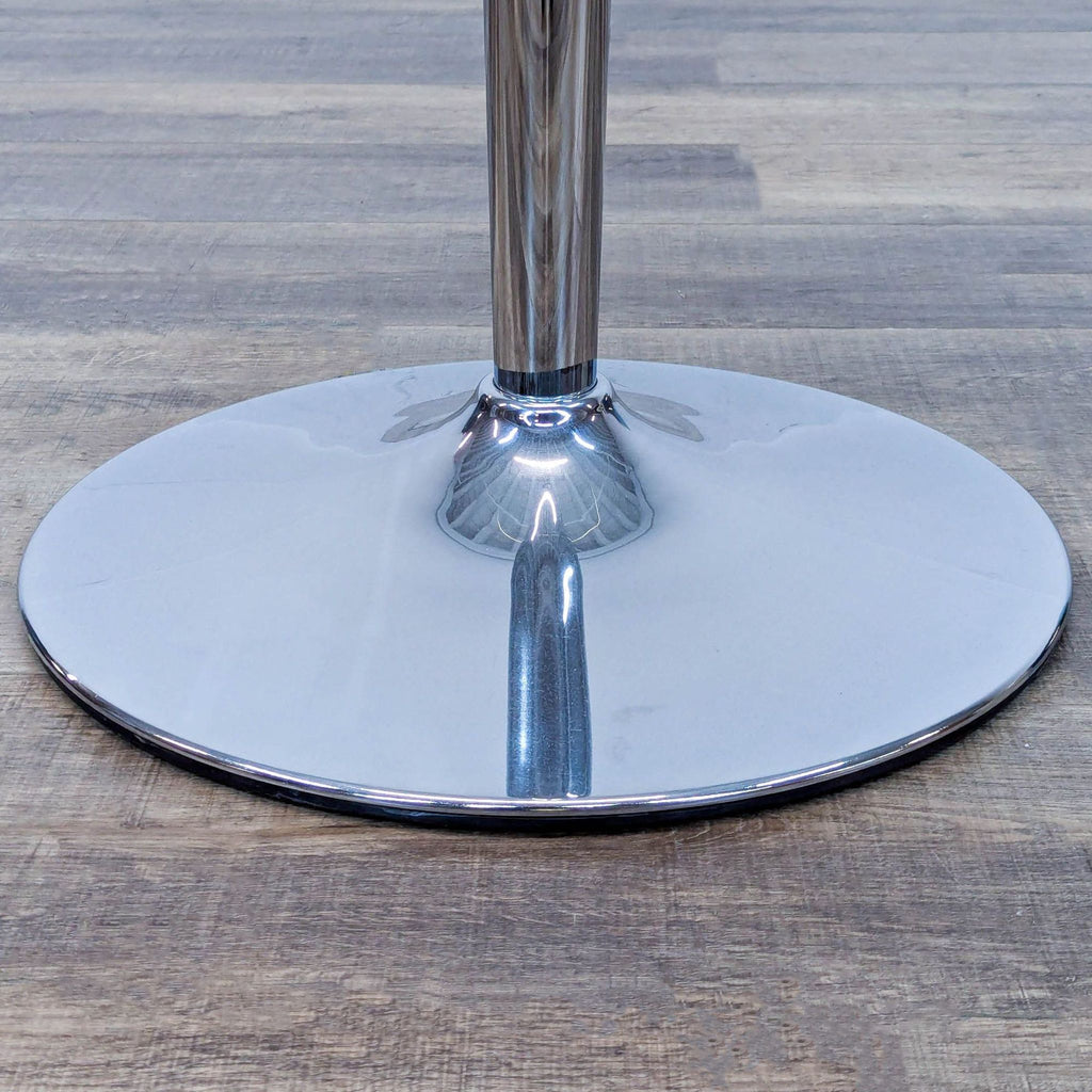 Close-up of the metal base of a two-seater Reperch dining table on wood floor.