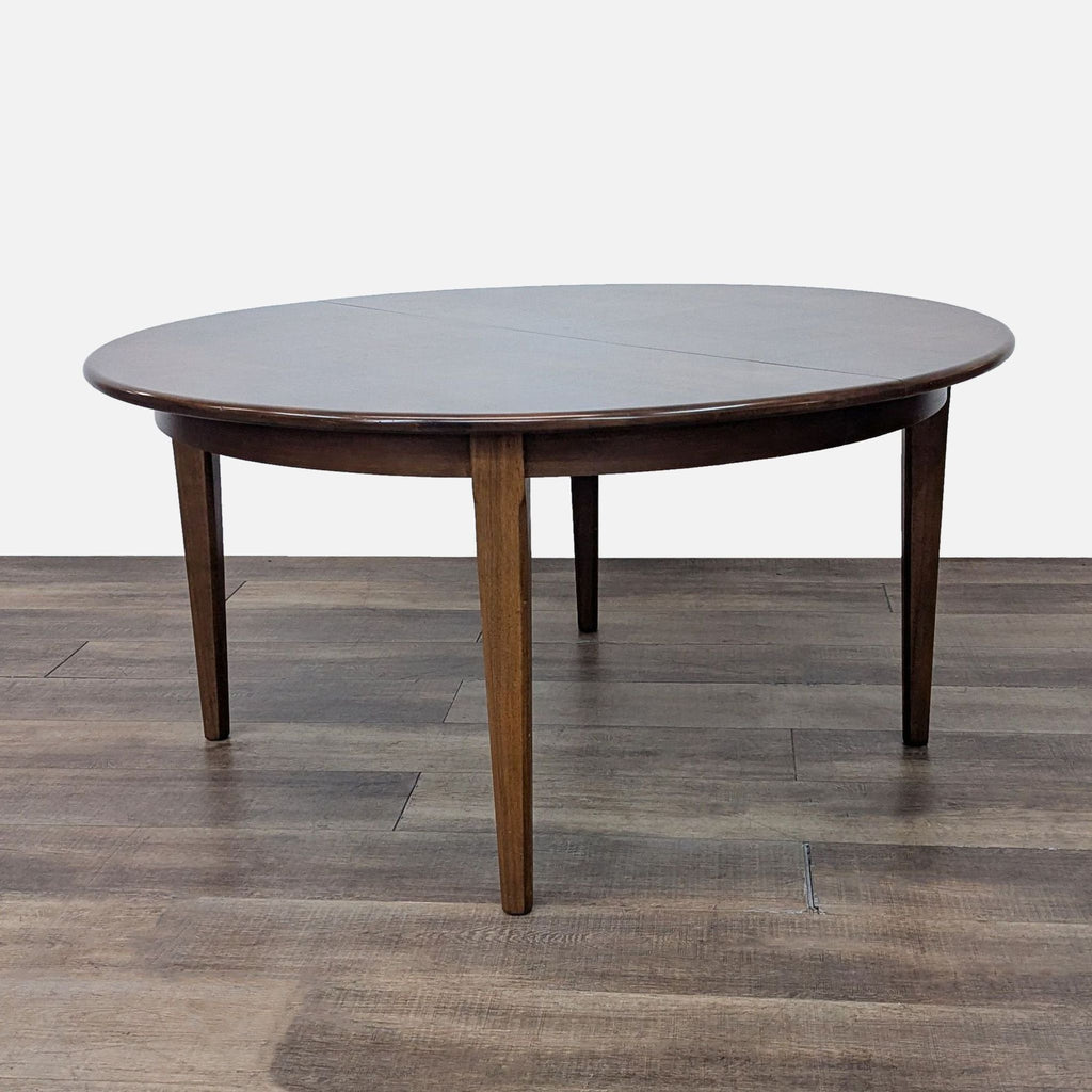 Round wooden dining table with smooth finish on wooden floor.