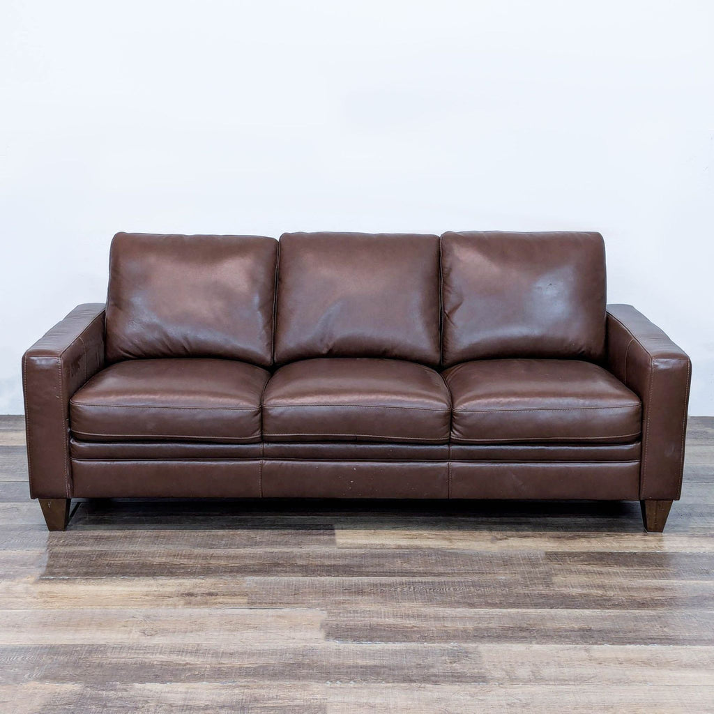 Brown leather 3-seat sofa with track arms and tapered legs.