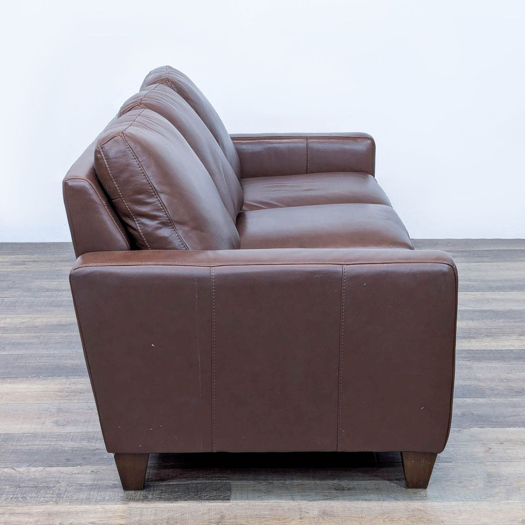 Side view of brown leather sofa with plush cushions and track arms.