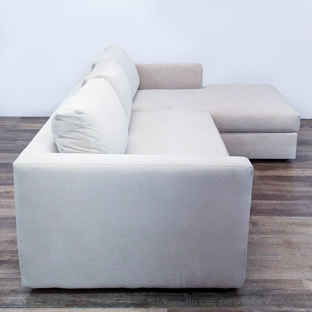 Side view of a cream sectional sofa with plush velvet fabric, offering comfort and style in a modern space.  