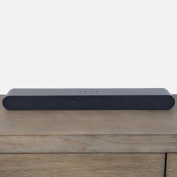 Samsung soundbar on a wooden surface, showcasing its sleek, modern design for enhanced audio experience.