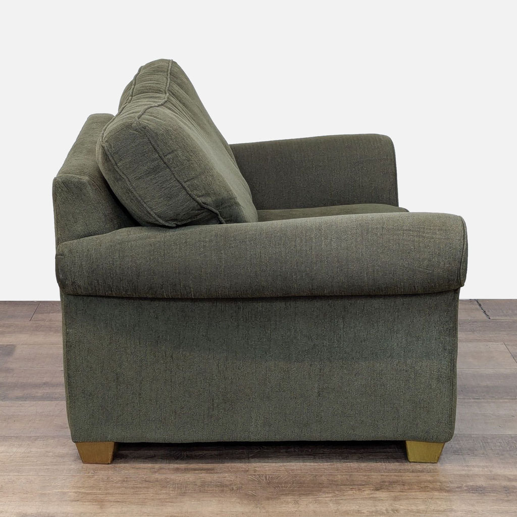 Side view of a Bauhaus lounge chair featuring rolled arms and plush cushions on wood feet.