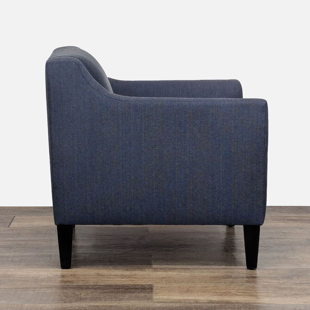2. Side view of a modern lounge chair in blue fabric with cutaway arms and tapered legs by Crate & Barrel.