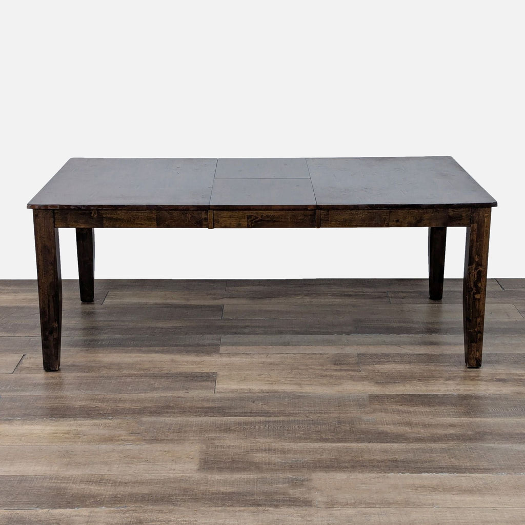 Reperch dining table with extendable leaf, shown on wooden floor.
