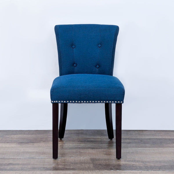 Accent chair with wood legs, tufted back, and nailhead trim in a lounge setting.