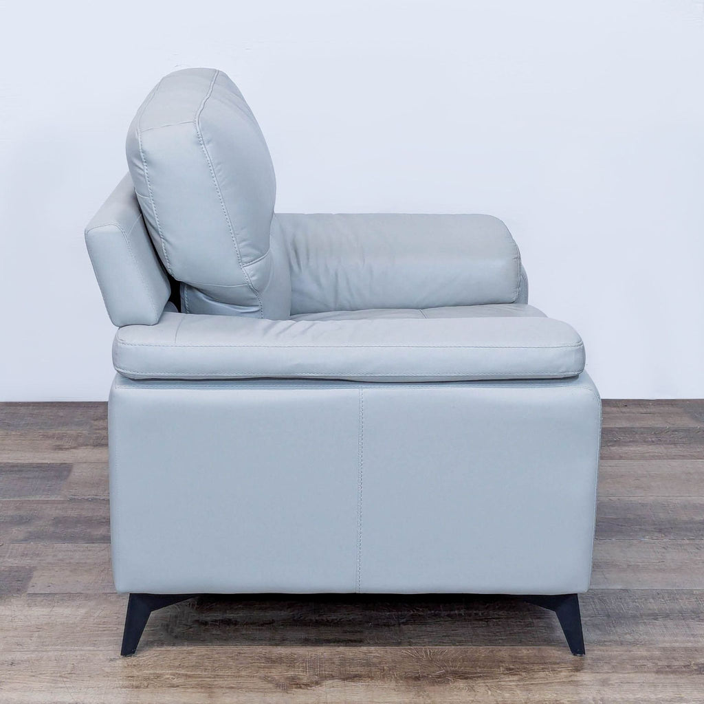 Side view of the Mischa lounge chair, featuring sleek silver faux leather and contoured arms.