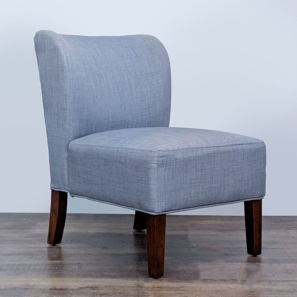 Angled view of a gray slipper chair featuring wooden legs and linen upholstery.