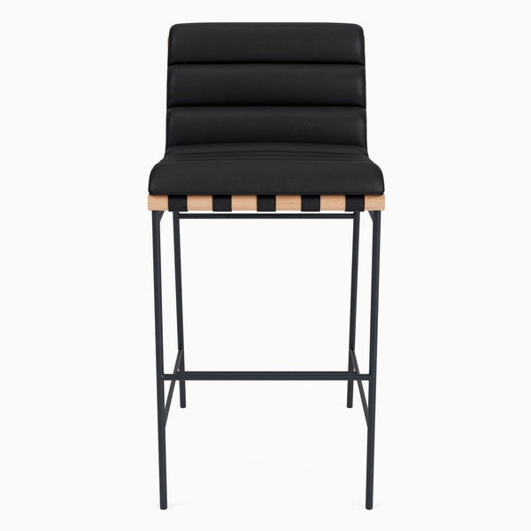 Front view of a modern stool with channel-tufted leather and oak accents.