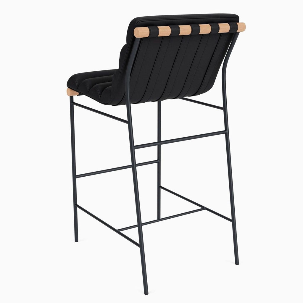 Back angle of a black tufted stool featuring oak and strap details.