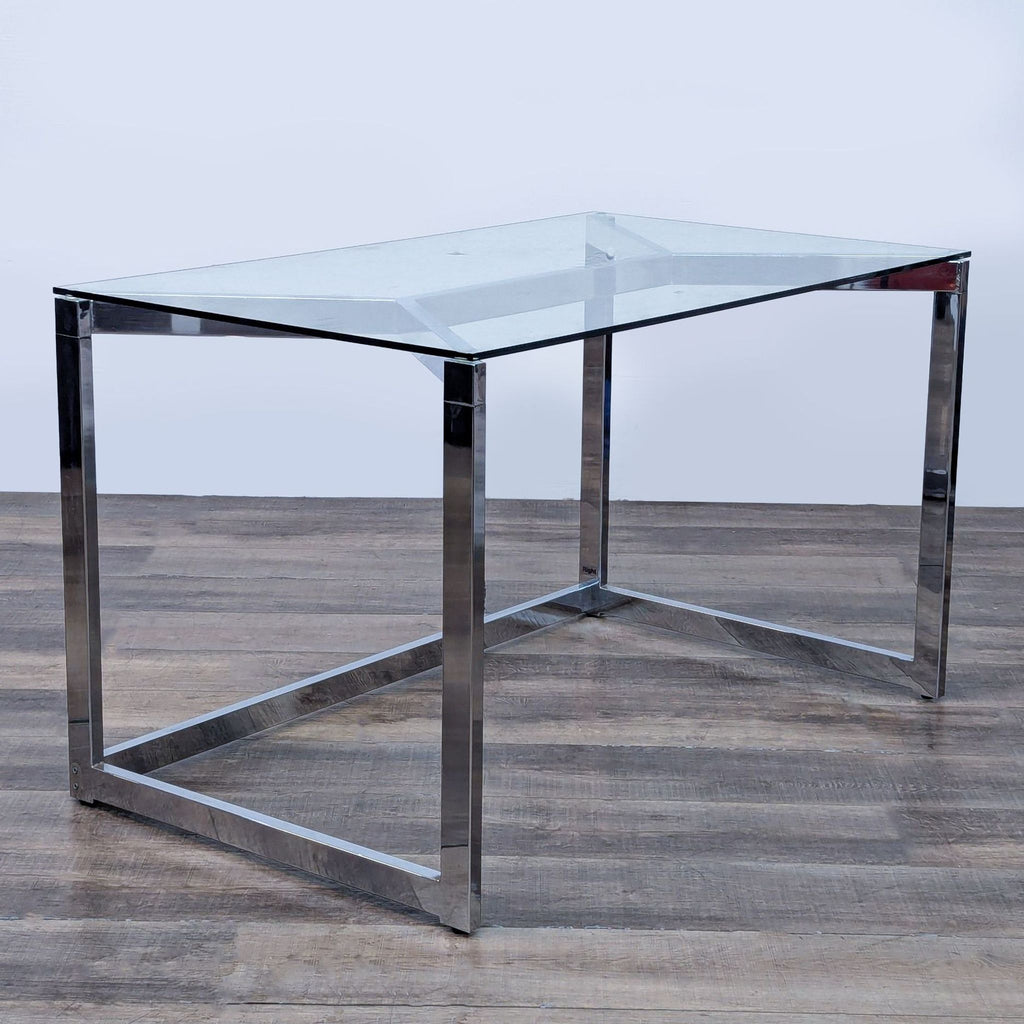 Minimalist desk by CB2 with a chrome metal frame and tempered glass top.