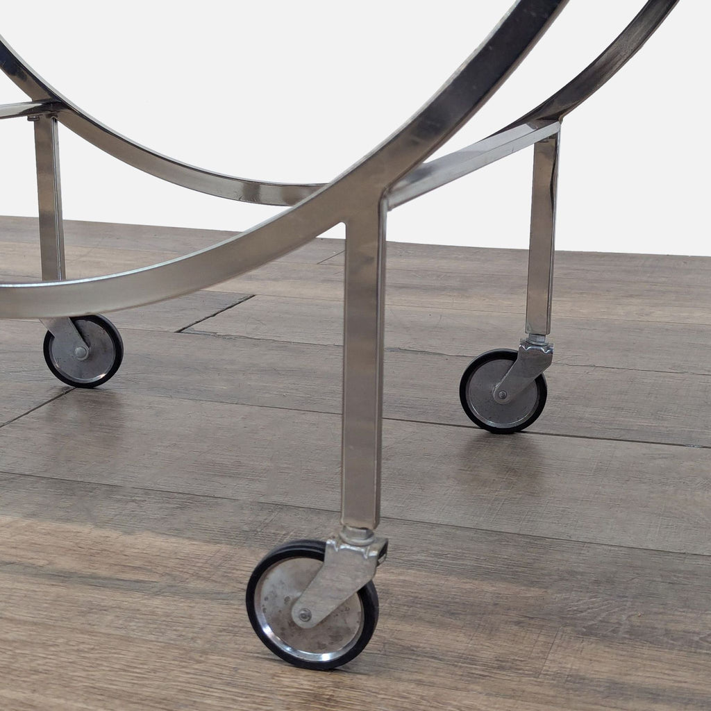 Close-up of caster wheels on a metal frame with a wooden floor backdrop.
