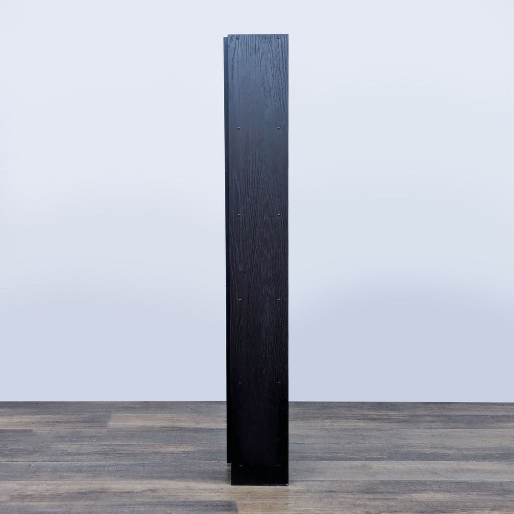 Rear view of a tall black bookshelf, showcasing a flat panel design.