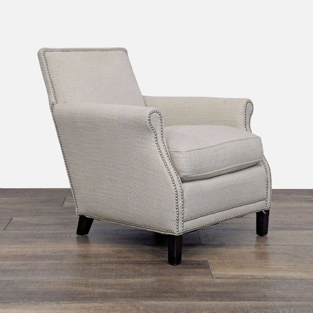 Angled view of a beige upholstered chair with dark wooden legs.