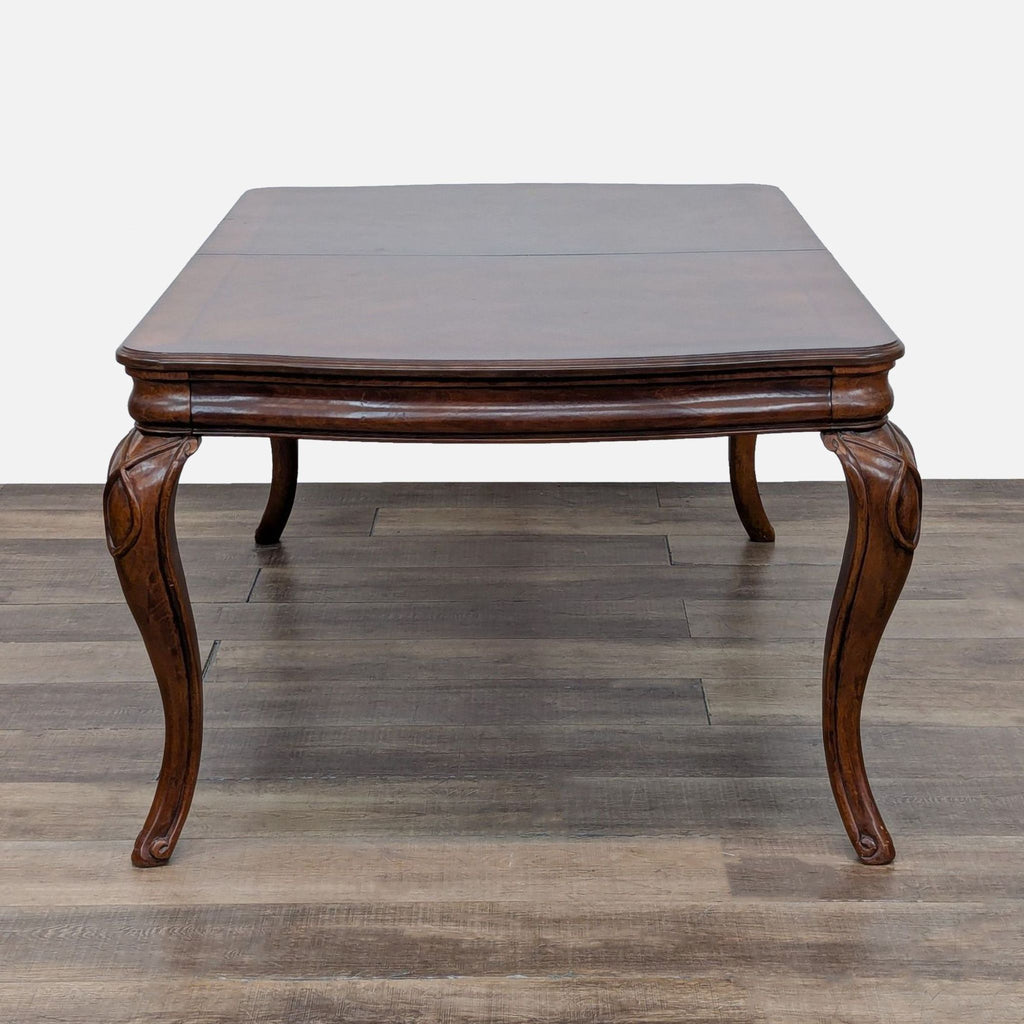 Elegant wooden dining table by Reperch, featuring ornate cabriole legs and expandable design.