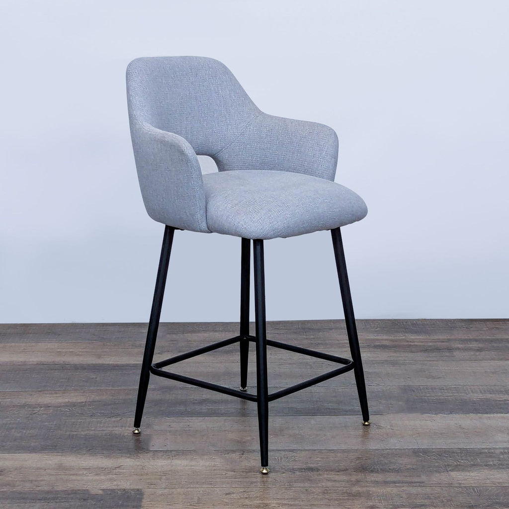 Side view of gray cushioned bar stool featuring a sleek design with black metal legs.