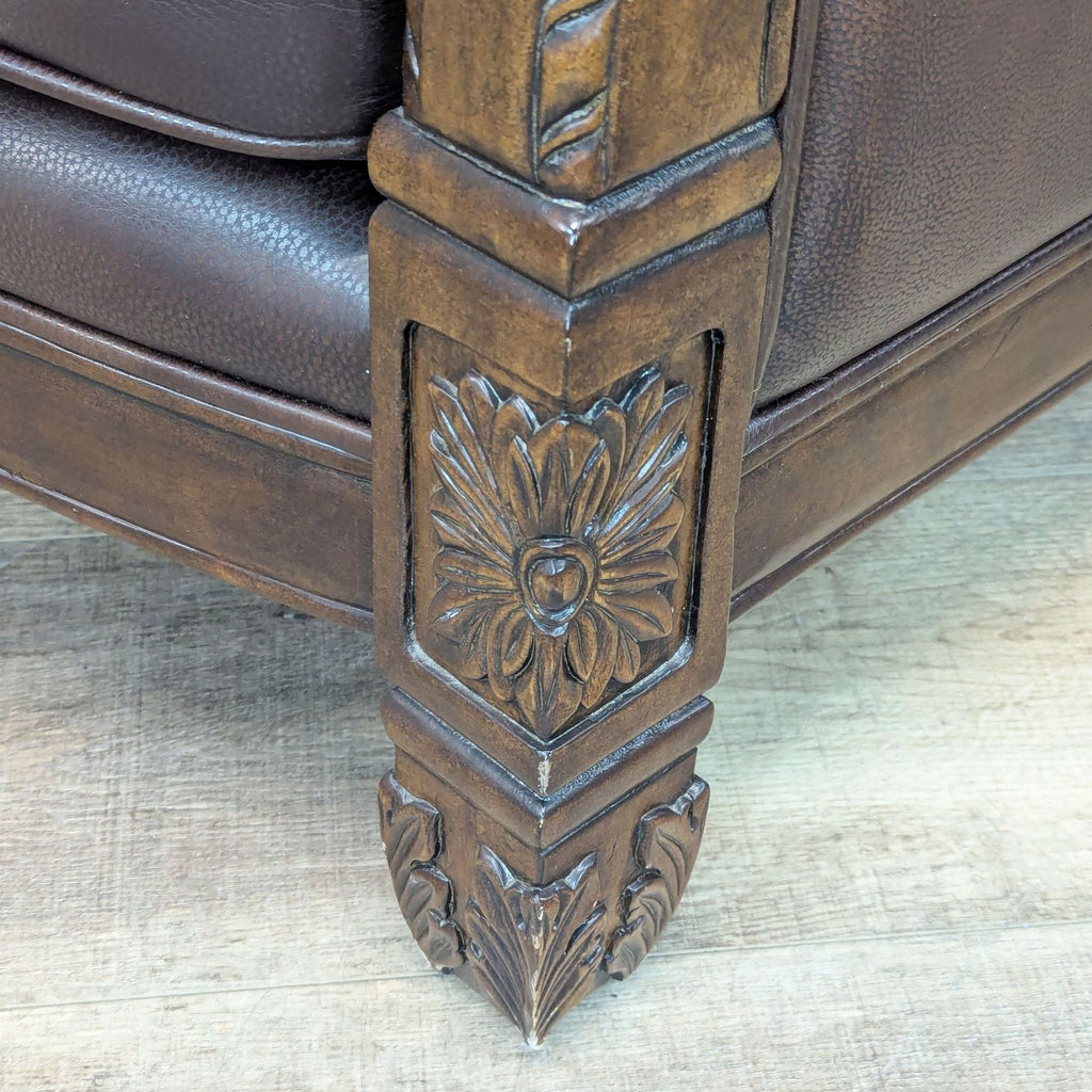 Close-up of intricate wood carvings on the base of a Michael Amini lounge chair.