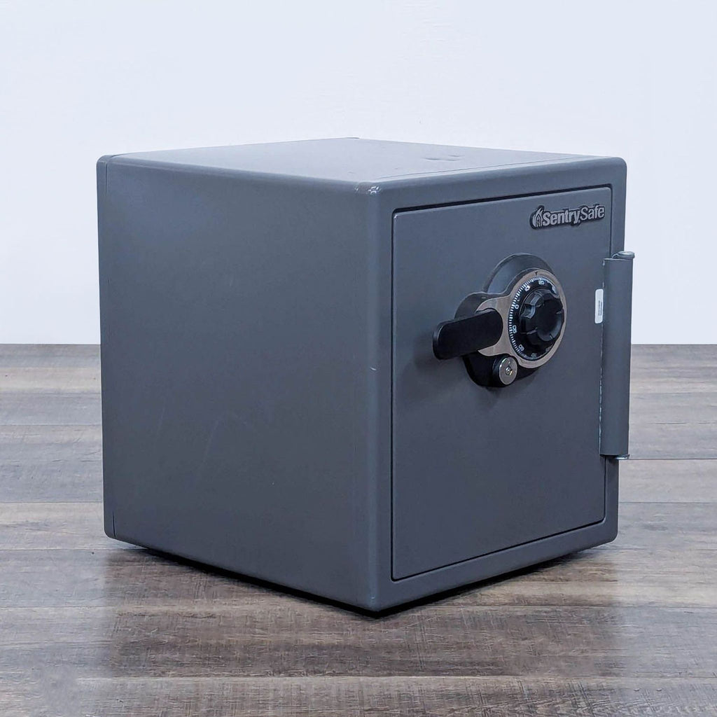 Side angle of a grey SentrySafe safe on a wooden surface.