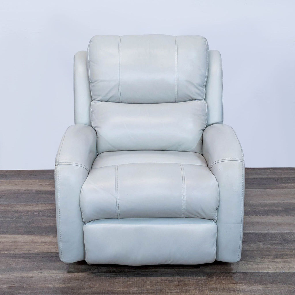 Front view of a white leather recliner with an adjustable headrest on wooden floor.
