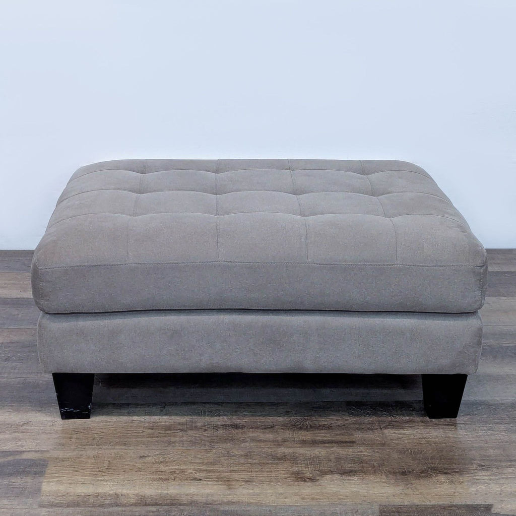 Tufted gray ottoman by Ashley Furniture, featuring dark square legs.