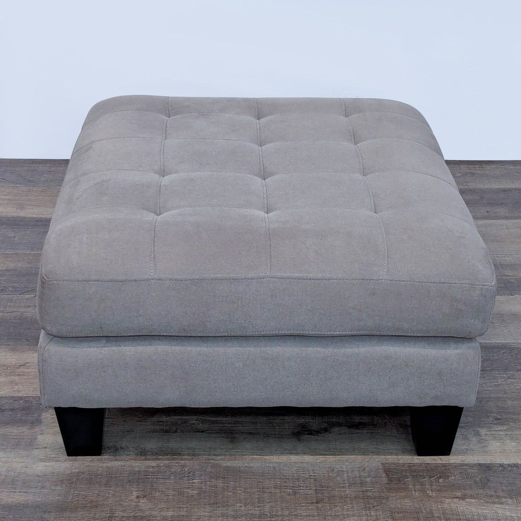 Rectangular Ashley Furniture ottoman in gray with wooden legs.