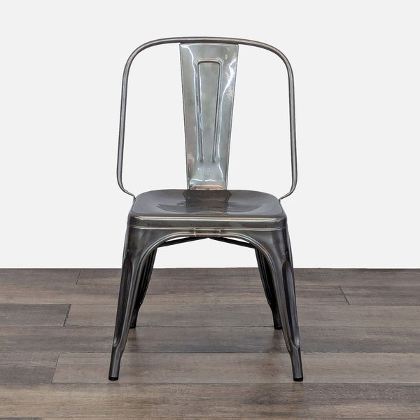Front view of a sleek, metal dining chair from Reperch on a wooden floor.