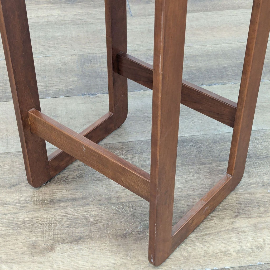 Close-up of wooden stool's sturdy legs and support.