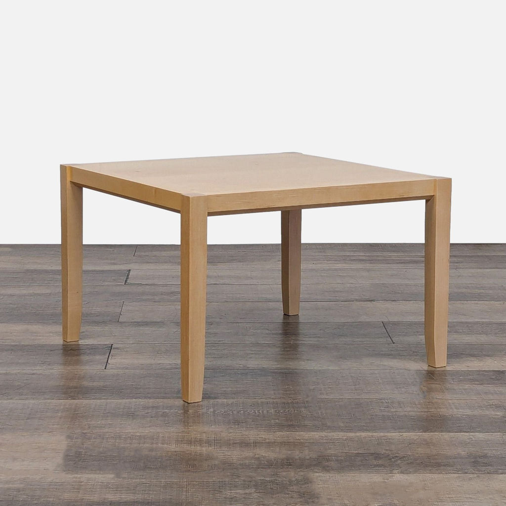 Square-shaped Reperch End Table with light wood tone, placed on dark wood flooring.