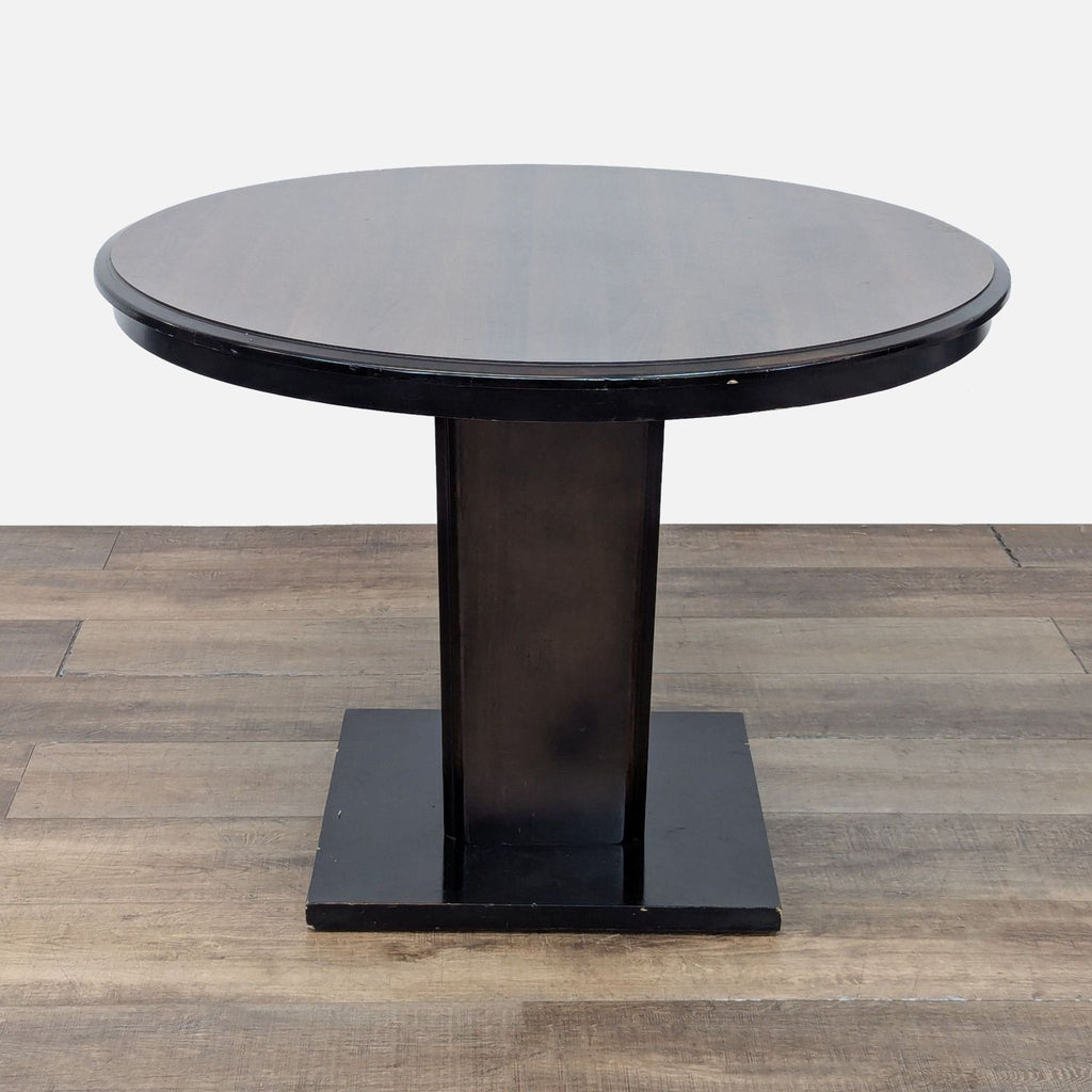 Single round wood dining table with dark pedestal base, part of Reperch Dining Set.