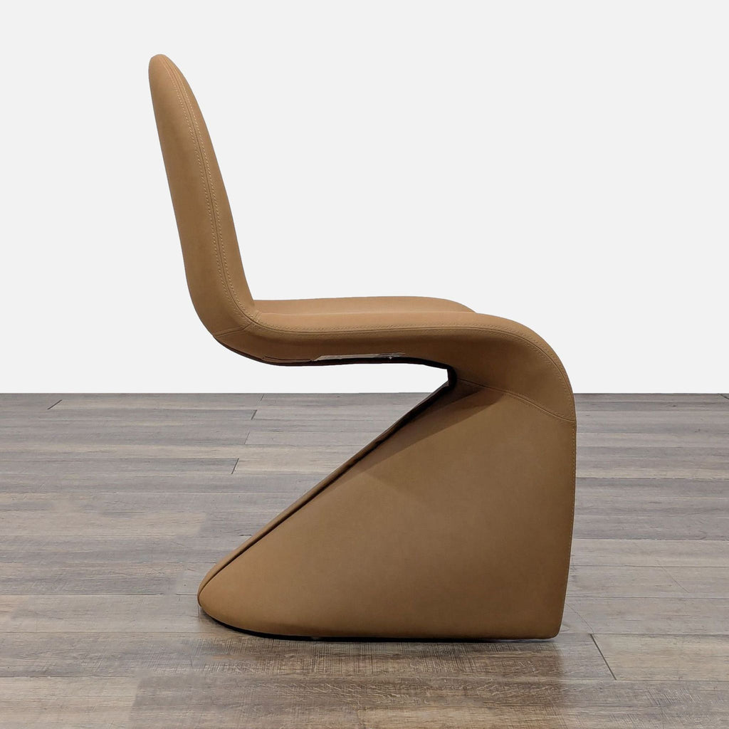 Side view of a stylish tan chair, featuring a modern sculptural design and vegan leather covering.