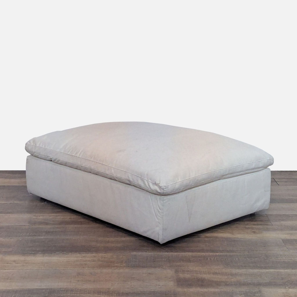 Elegant beige ottoman from Restoration Hardware on wooden floor.