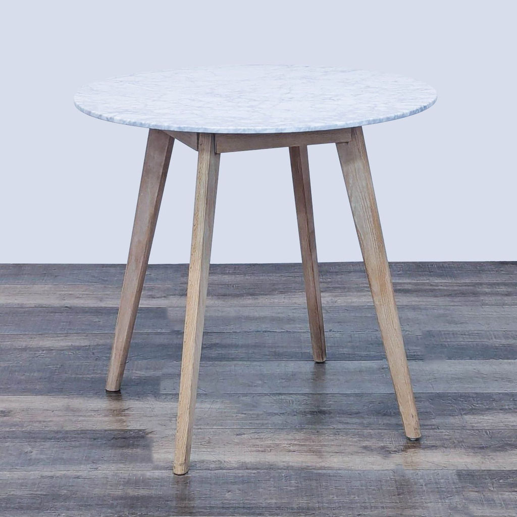 Round dining table with a marble top and oak legs by Article.