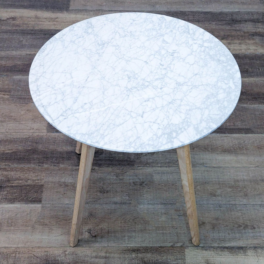 Top view of a round marble table with sturdy wooden legs.