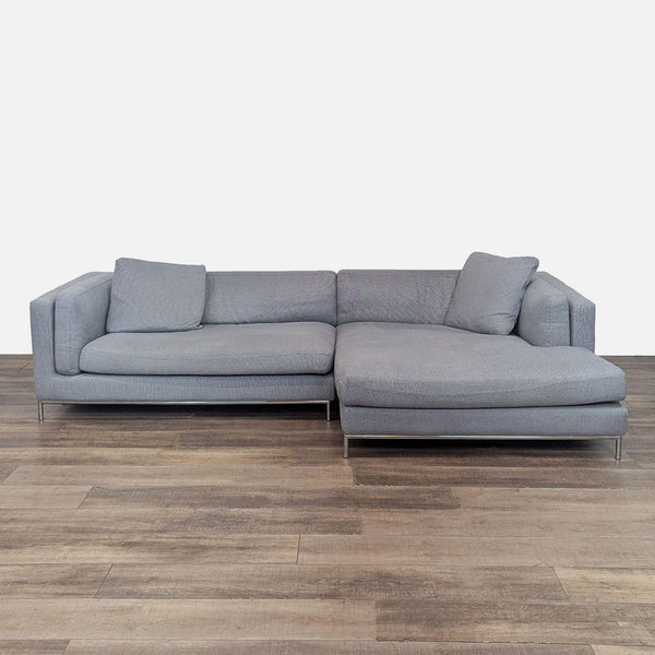 Gray sectional with right chaise on wooden floor, chrome legs.