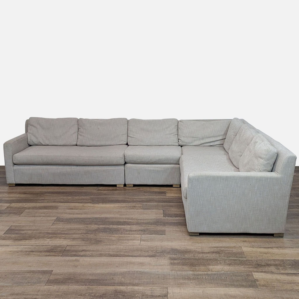 L-shaped upholstered sectional sofa with track arms on wooden floor.