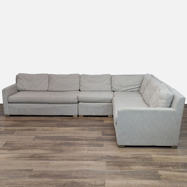 L-shaped upholstered sectional sofa with track arms on wooden floor.