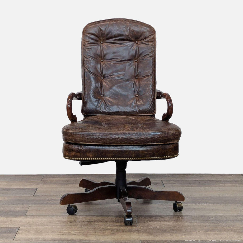 Front view of a tufted leather chair with wooden arms and base, featuring casters.