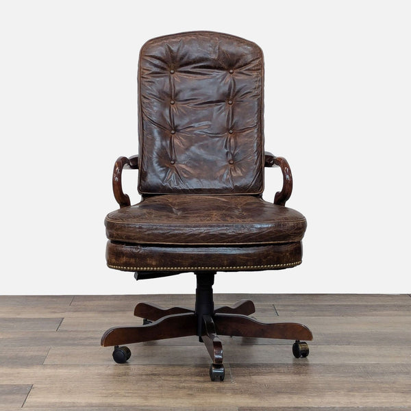 Front view of a tufted leather chair with wooden arms and base, featuring casters.